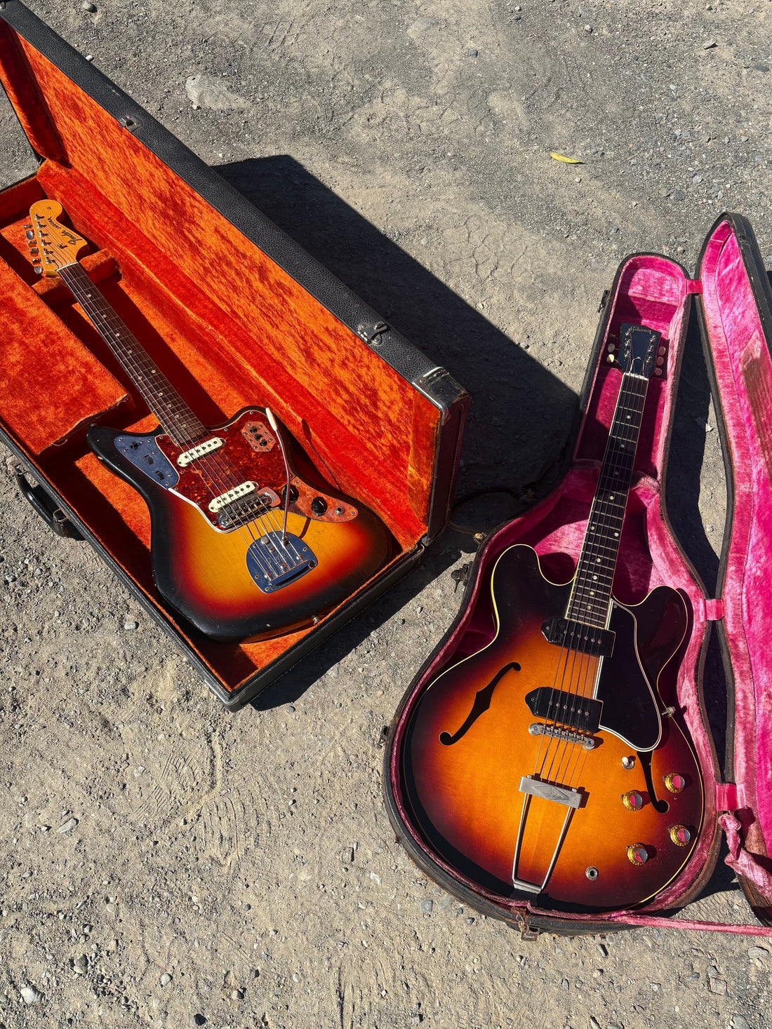 A collection of two vintage guitars, one Fender Jaguar on the left and one Gibson hollow body on the right, both in their original cases.