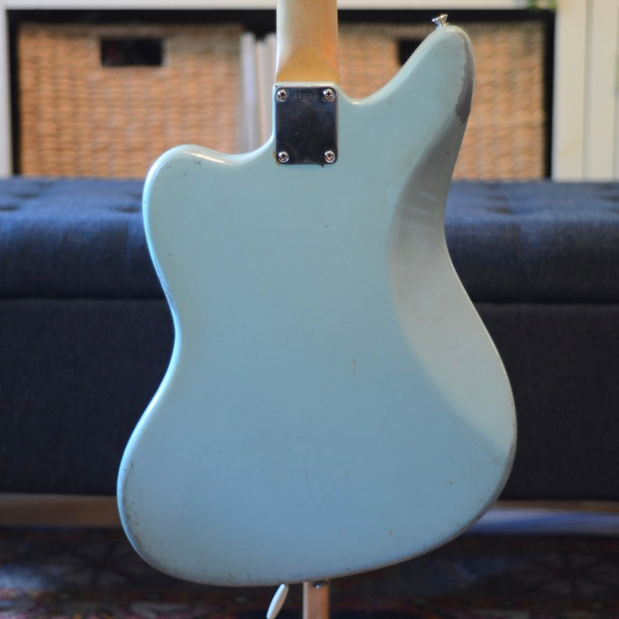 Back of blue electric guitar with a blurred sofa in the background
