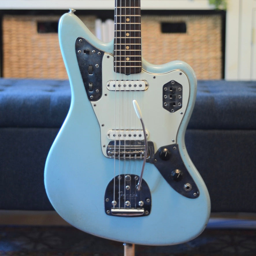 Light blue electric guitar on a stand with a blurred background