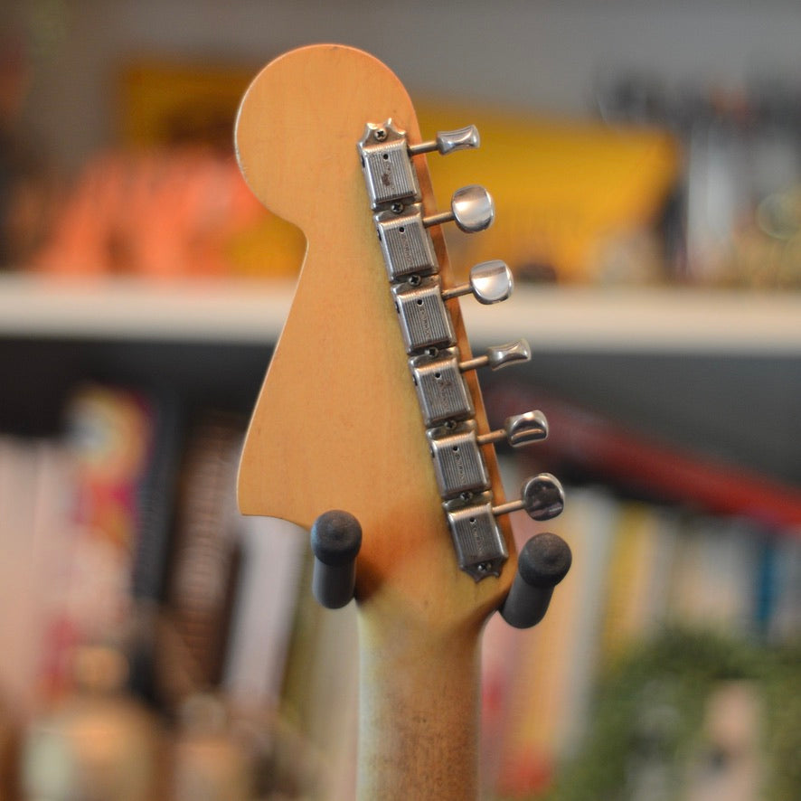 Close-up of back of Fender Jaguar headstock showing original Kluson tuners with blurred background