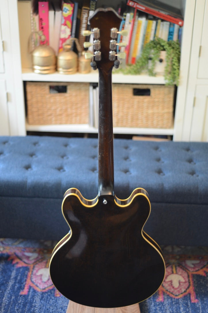 1967 Epiphone Riviera with brown back and sides seen from the back in front of a blue bench