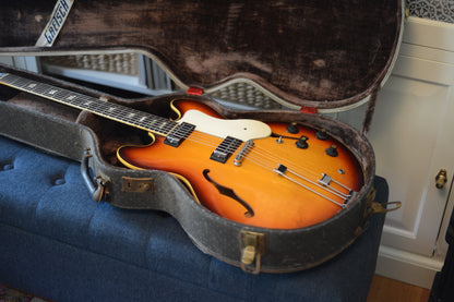 Sunburst electric guitar in a case on a blue surface